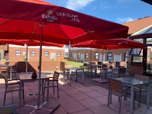 a group of tables and chairs with red umbrellas at Dragonfly Hotel Bury St Edmunds in Bury Saint Edmunds
