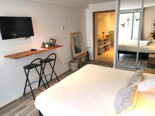 a room with two beds and a desk and a tv at Les Digues Vauban in Ciboure
