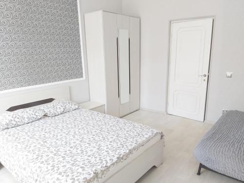 a white bedroom with a bed and a chair at РАЗЪЕЗЖАЯ ул 42 in Saint Petersburg