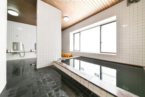 een badkamer met een zwembad en een groot raam bij 丸源旅館 無料朝食 全館wifi 準天然温泉 in Iwata