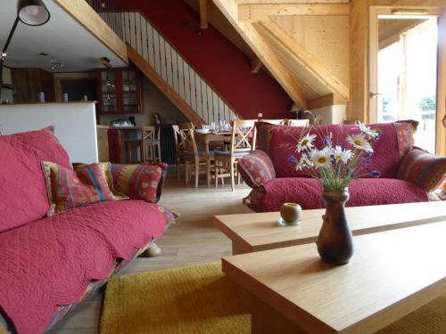 a living room with purple couches and a table with flowers at Ferme de la grande Moucherolle in Villard-de-Lans