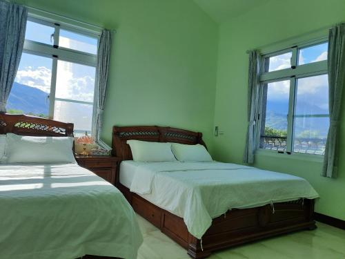 two beds in a bedroom with two windows at Ode to Mansions B&B in Chishang