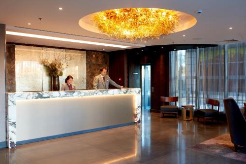 Ein Mann und eine Frau stehen an einer Theke in einer Lobby in der Unterkunft Hyatt Regency London Albert Embankment in London