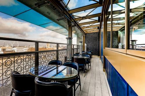a restaurant with tables and chairs on a balcony at Hyatt Regency London Albert Embankment in London