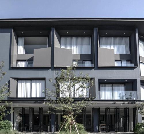 a black building with a tree in front of it at CREW Hotel in Chiang Mai