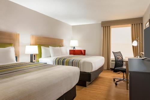 a hotel room with two beds and a desk at Country Inn & Suites by Radisson, North Little Rock, AR in North Little Rock