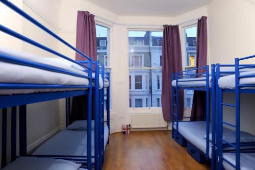 three bunk beds in a room with a window at Saint James Backpackers in London