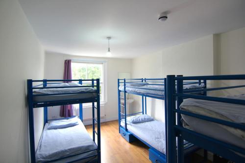 a bedroom with two bunk beds and two windows at Saint James Backpackers in London