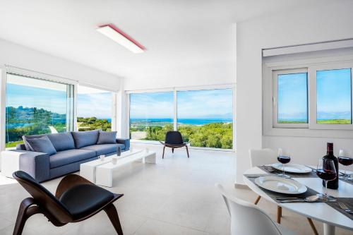 a living room with a couch and a table and chairs at Villa Nafsika by PosarelliVillas in Perítheia