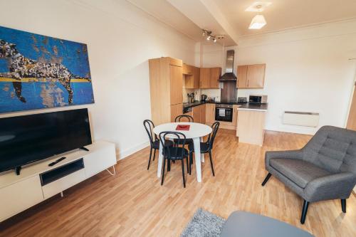 a living room with a table and chairs and a television at The Stay Company, Dalby House in Derby