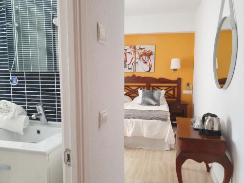 a bedroom with a bed and a bathroom with a sink at Hotel Boutique Las Arenas in Es Cana