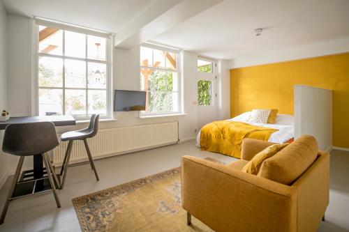 a bedroom with a bed and a desk and a chair at Bed&Breakfast Tussen de Poorten in Kampen