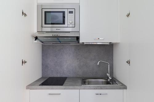 eine Küche mit einer Spüle und einer Mikrowelle in der Unterkunft Cavour Luxury Home in Rom