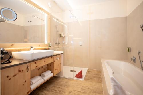 a bathroom with a sink and a tub and a shower at Thermenhotel PuchasPLUS Stegersbach in Stegersbach