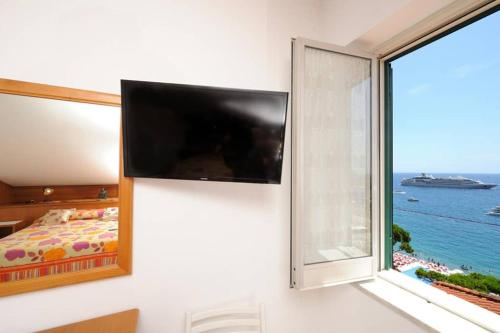 a bedroom with a flat screen tv and a window at Mamma Rosanna - Apartment in Amalfi with terrace in Amalfi