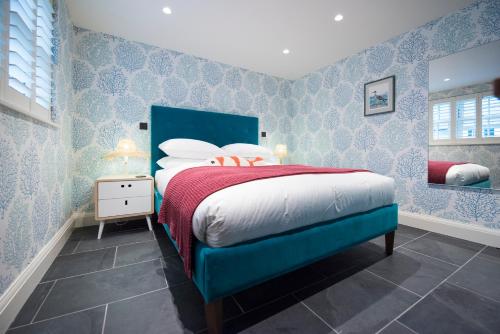 a blue bedroom with a bed with a red blanket at Juliot 5 Star Gold Award Luxury Cottage in St Ives