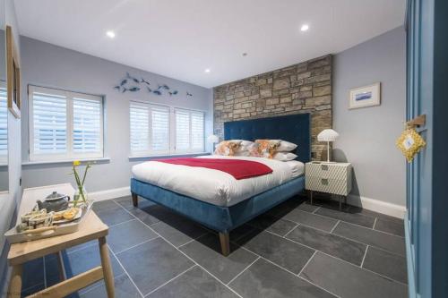um quarto com uma cama azul e uma parede de pedra em The Garth 5 Star Gold Luxury Cottages em St. Ives
