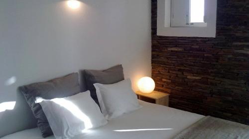 a bedroom with a bed with pillows and a brick wall at Monte Falperras in Mourão