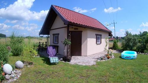 a small house with a red roof in a yard at Noclegi Pod Dachem pokoje gościnne domek letniskowy na wynajem agroturystyka wakacje in Sajzy