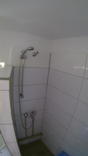 a shower in a bathroom with a white wall at Noclegi Pod Dachem pokoje gościnne domek letniskowy na wynajem agroturystyka wakacje in Sajzy