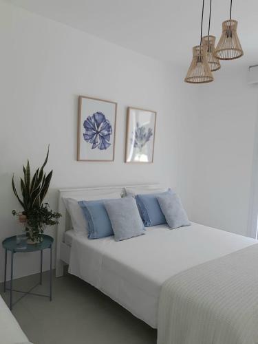 a white bedroom with a bed with blue pillows at Cocciu d’amuri in Terrasini