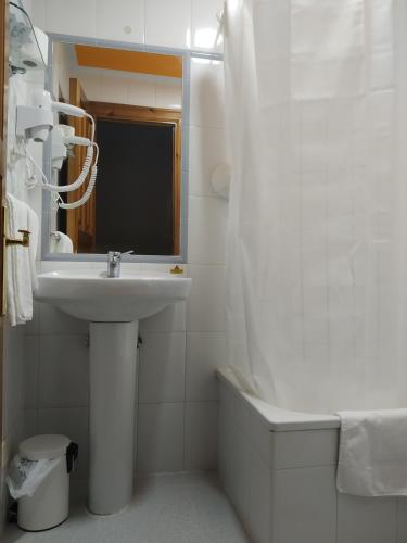a white bathroom with a sink and a mirror at Hotel Los Robles in Cangas de Onís