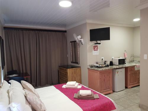 a hotel room with a bed and a kitchen at Huis van Seisoene in Klerksdorp