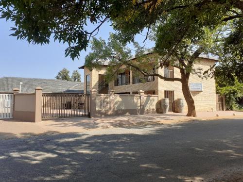 a house with a fence and a tree at Huis van Seisoene in Klerksdorp