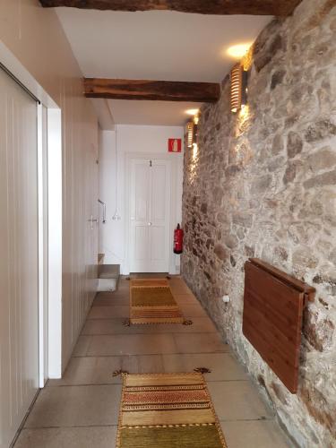 a hallway with a stone wall and a hallway with rugs at Pensión con Encanto San Martiño Pinario in Santiago de Compostela