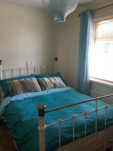 1 dormitorio con cama con sábanas azules y ventana en Hornhead Mews, Hornhead, en Dunfanaghy