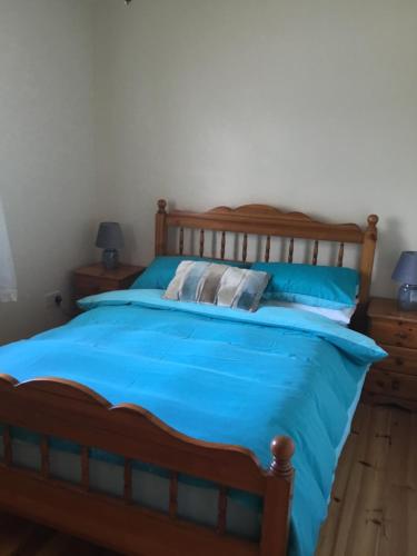 1 dormitorio con cama de madera con sábanas azules en Hornhead Mews, Hornhead, en Dunfanaghy