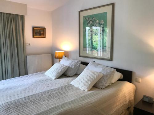 una camera da letto con letto, lenzuola e cuscini bianchi di Villa 't Haasduin a Wijk aan Zee