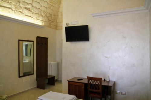 a room with a desk and a television on a wall at Rooms Dimora Arco - Affitti Brevi Italia in Monte SantʼAngelo