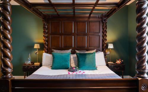 um quarto com uma grande cama de madeira com paredes verdes em The Vicarage em Holmes Chapel