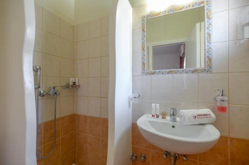 a bathroom with a sink and a shower with a mirror at Panormos Hotel and Studios in Naxos Chora