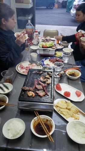 a table with a grill and many plates of food at あかがね荘 in Sumino