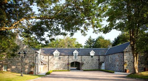 an old stone building with a driveway in front of it at Trump MacLeod House & Lodge, Scotland in Balmedie