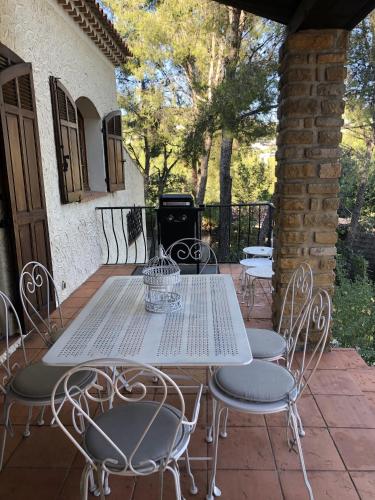 une table blanche et des chaises sur une terrasse dans l'établissement Villa provençale – grand jardin - 2 chambres, à Bandol