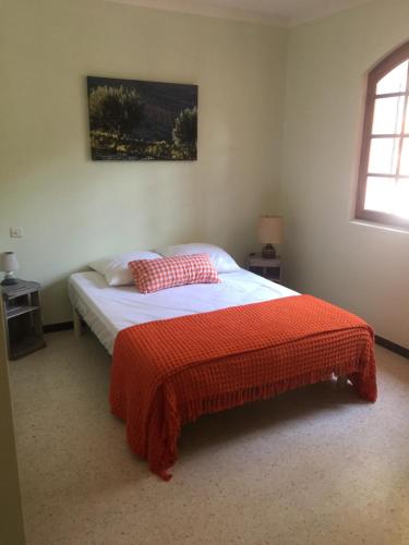 Villa provençale – grand jardin - 2 chambres في باندول: غرفة نوم مع سرير مع بطانية حمراء عليه