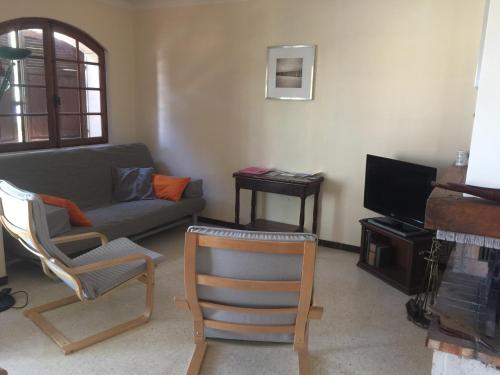 uma sala de estar com um sofá e cadeiras e uma televisão em Villa provençale – grand jardin - 2 chambres em Bandol