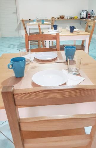 a wooden table with plates and glasses on it at Pepi B&B in Santa Maria di Castellabate