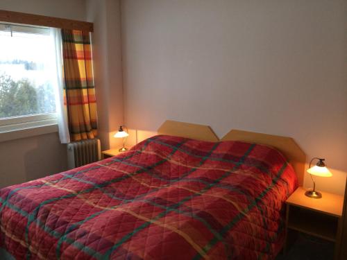a bedroom with a bed with a colorful comforter and two lamps at Vormsund Golf Hotell in Vormsund