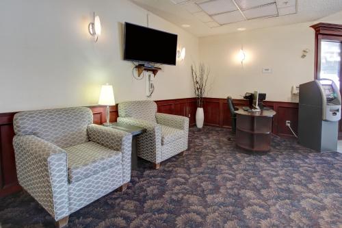 um quarto de hotel com duas cadeiras e uma televisão de ecrã plano em Ramada by Wyndham Nisku Edmonton Airport em Nisku