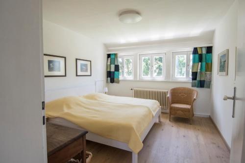 een slaapkamer met een bed, een stoel en ramen bij Haus Hirt - Idyllisch wohnen zwischen Augsburg und München in Klosterlechfeld
