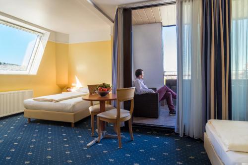 a hotel room with a bed and a man sitting on a chair at Aparthotel Astro - Nichtraucherhotel in Stuttgart