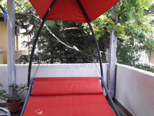 a swing on a porch with a red umbrella at Morska Zvezda Guest house in Pomorie