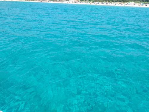 a large body of blue water with a beach at Brezza di mare appartamento in Villa con giardino e spiaggia ,casa vacanze al mare in Quartu SantʼElena