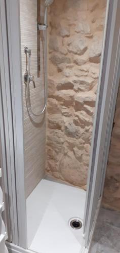 La salle de bains est pourvue d'une douche et d'un mur en pierre. dans l'établissement Via Pezza 100, à Raguse