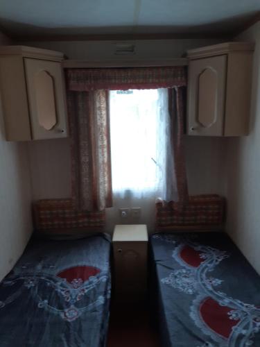 a small room with two beds and a window at Domek holenderski in Łuka
