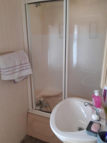 La salle de bains est pourvue d'une douche et d'un lavabo blanc. dans l'établissement Domek holenderski, à Łuka